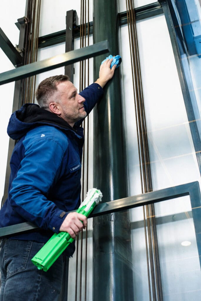 Een glazenwasser die een lift schoonmaakt
